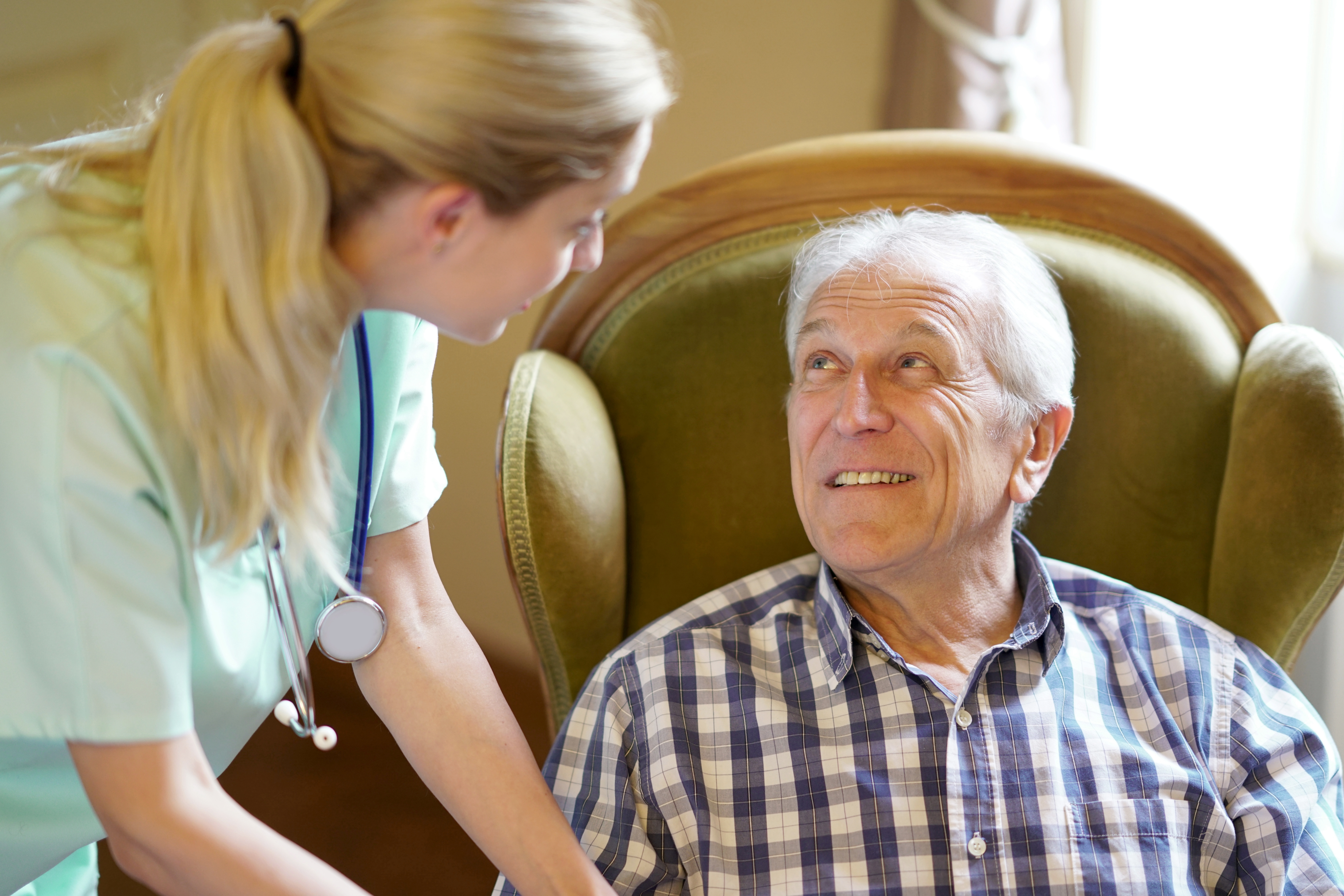 Happy elderly man looking at a nurse taking care of him