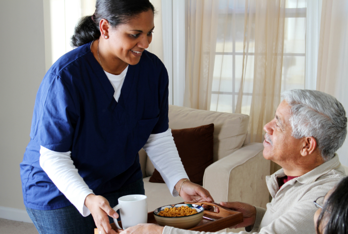 Home Care worker giving breakfast to elderly man