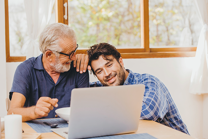 Son and elderly father happy moment looking at laptop