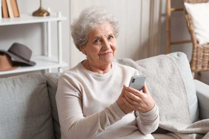 woman smiling as she searches online, old woman on the phone, old woman with goof wifi and phone signal, woman stays connected during covid