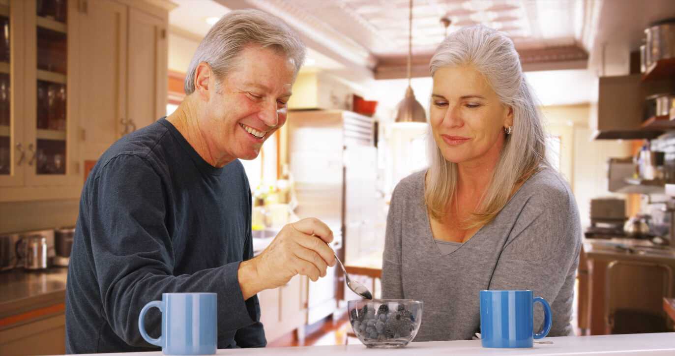 older couple eating blueberries and drinking coffee, retired married couple having breakfast, nutritious breakfast