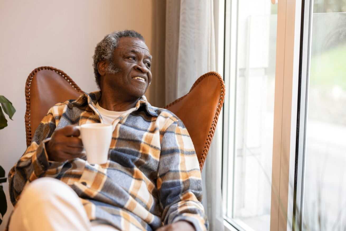 man happy after finding a care home he can trust, content older man drinking tea after speaking to autumna about care services with good infection control and prevention processes