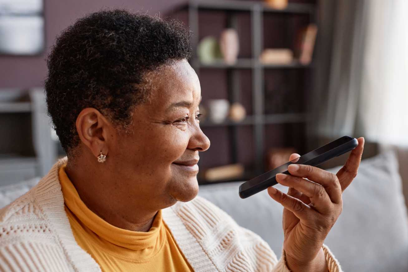 black older woman uses the phone to call Autumna for advice about funding her home care services
