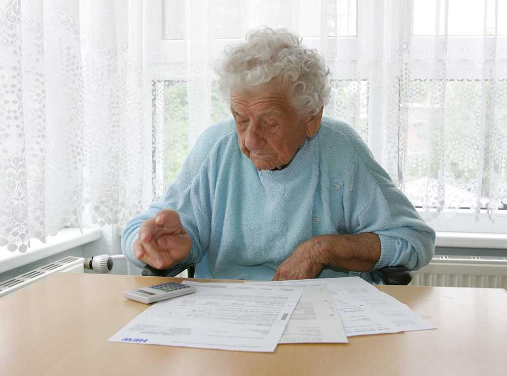 Elderly lady working out the cost of nursing home care in Scotland at table