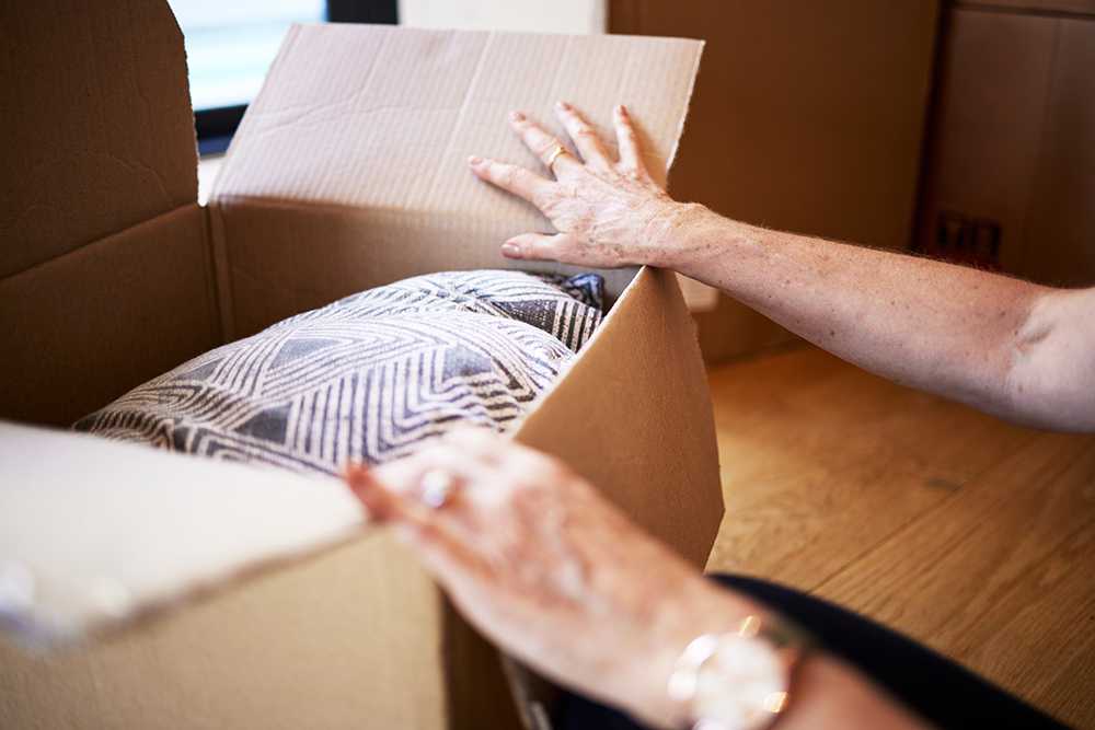 Moving to a care home in a different area. Picture of elderly hands opening a box