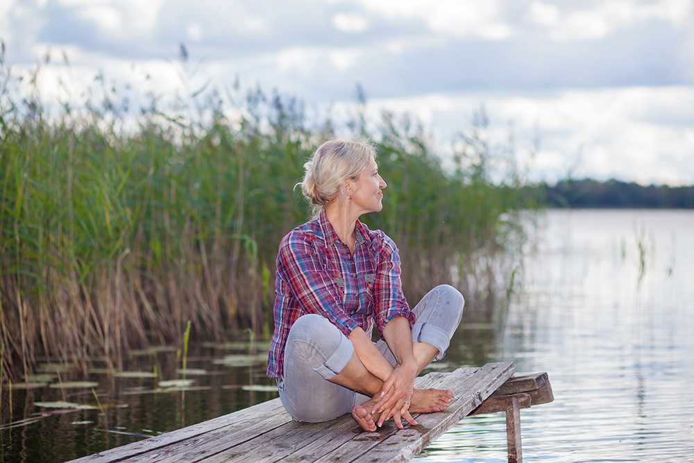 Woman sits alone on a pier while on carer's leave