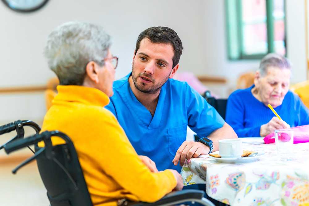 Young man with elderly person in yellow sweat top. Person centred values in care