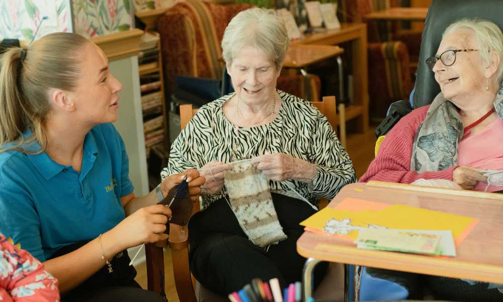 Care worker chatting with two elderly residents during an activity at a care home.