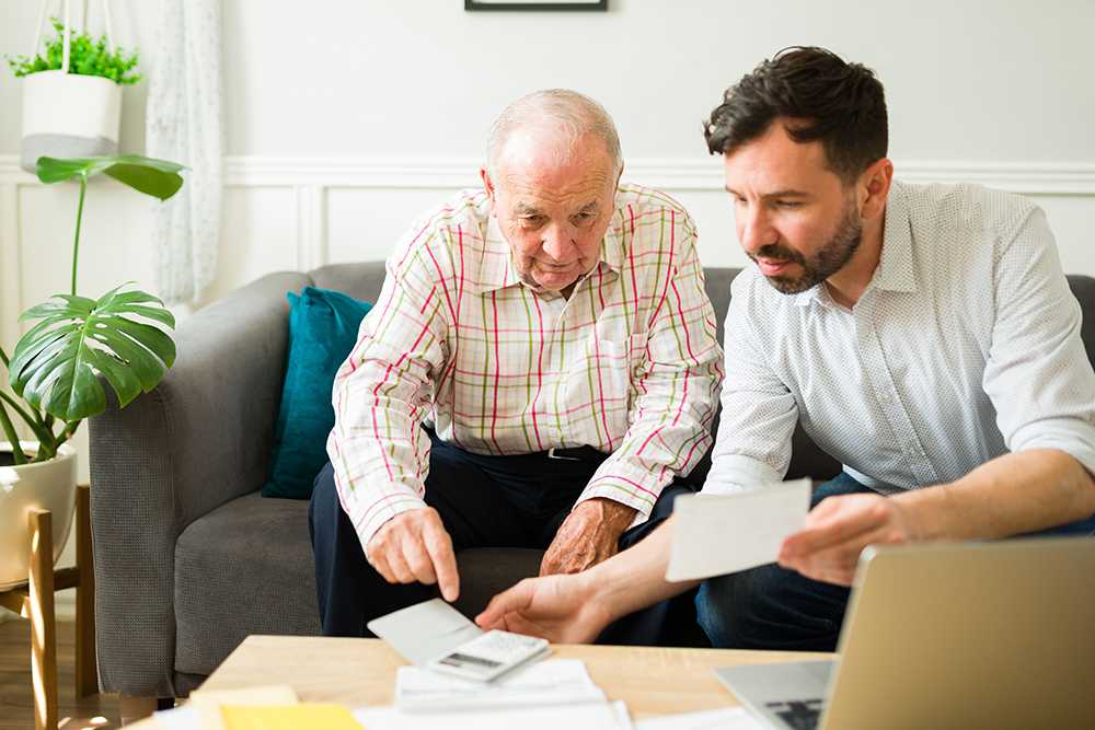 Elderly man and younger man discussing adult social care funding