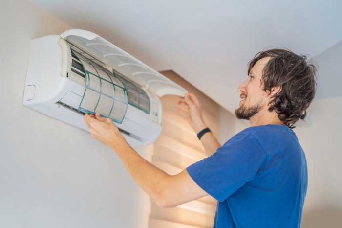 man installing air filter in a care home, man with brown hair and a blue t shirt fitting an air filter, infection control and prevention techniques in care homes