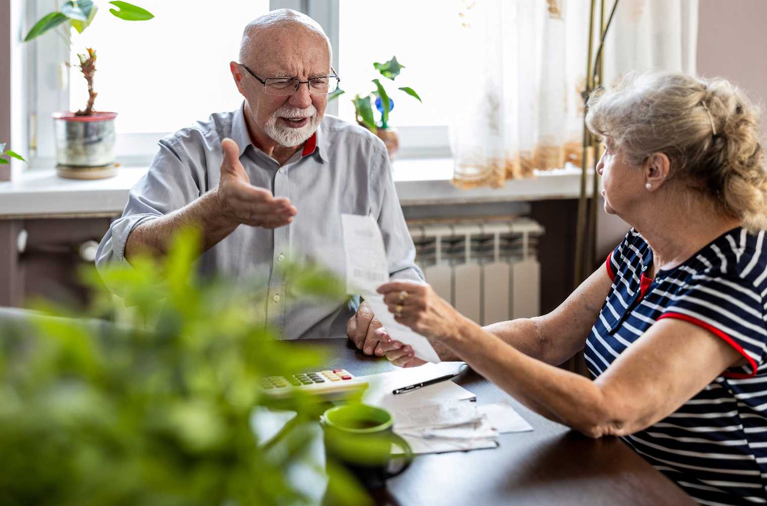 Two retirees discuss their financial situation over the kitchen table