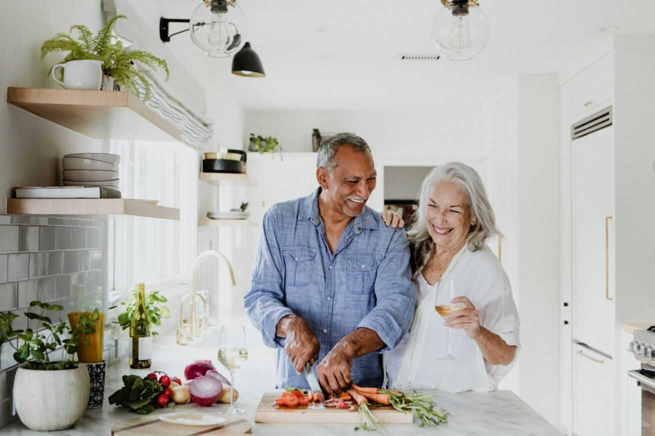 older couple cooking together, cooking nutritious food when you retire, man and woman smiling in the kitchen