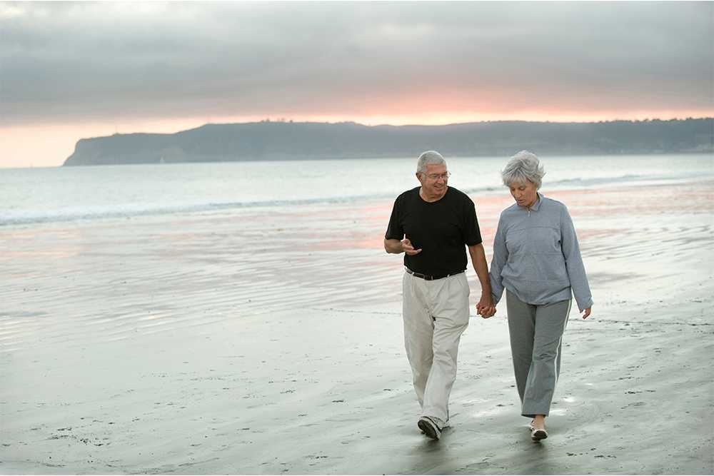 Senior couple walking by the sea on a beach