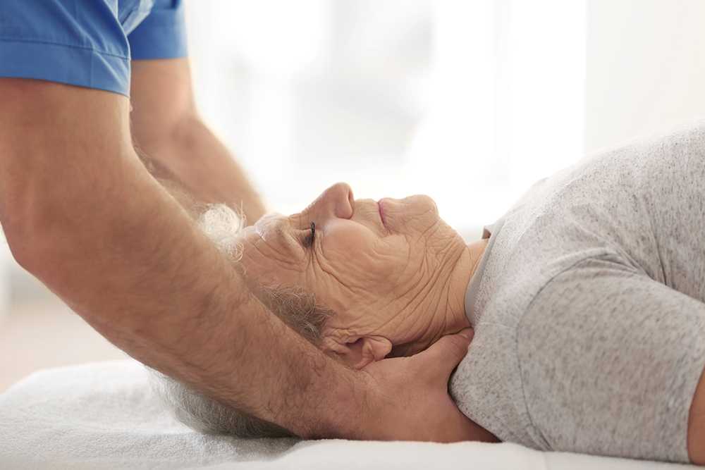 Elderly lady receiving head massage from nurse