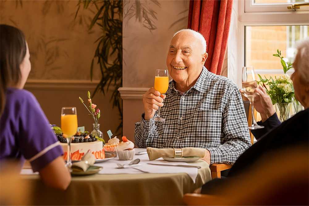 Older man sitting at table with orange juice at day centres for elderly in kent