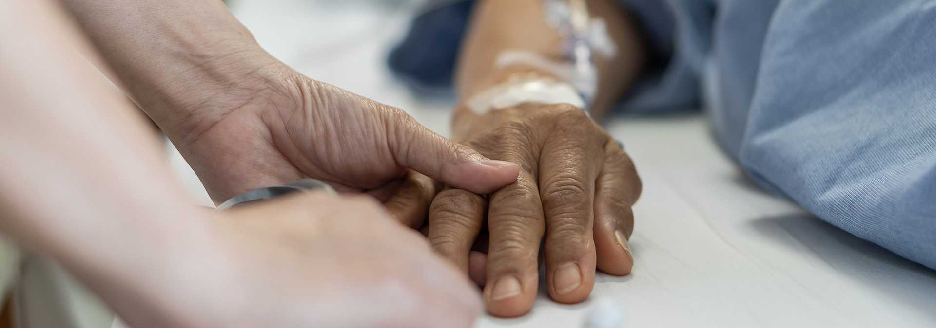 The hands of a young nurse holding those of a older person