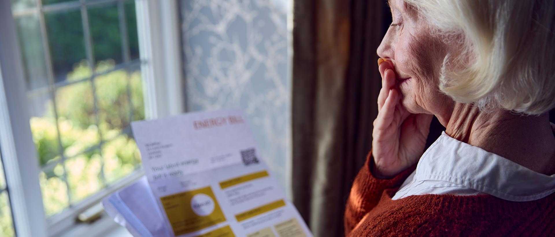 A senior woman studies her latest energy bill