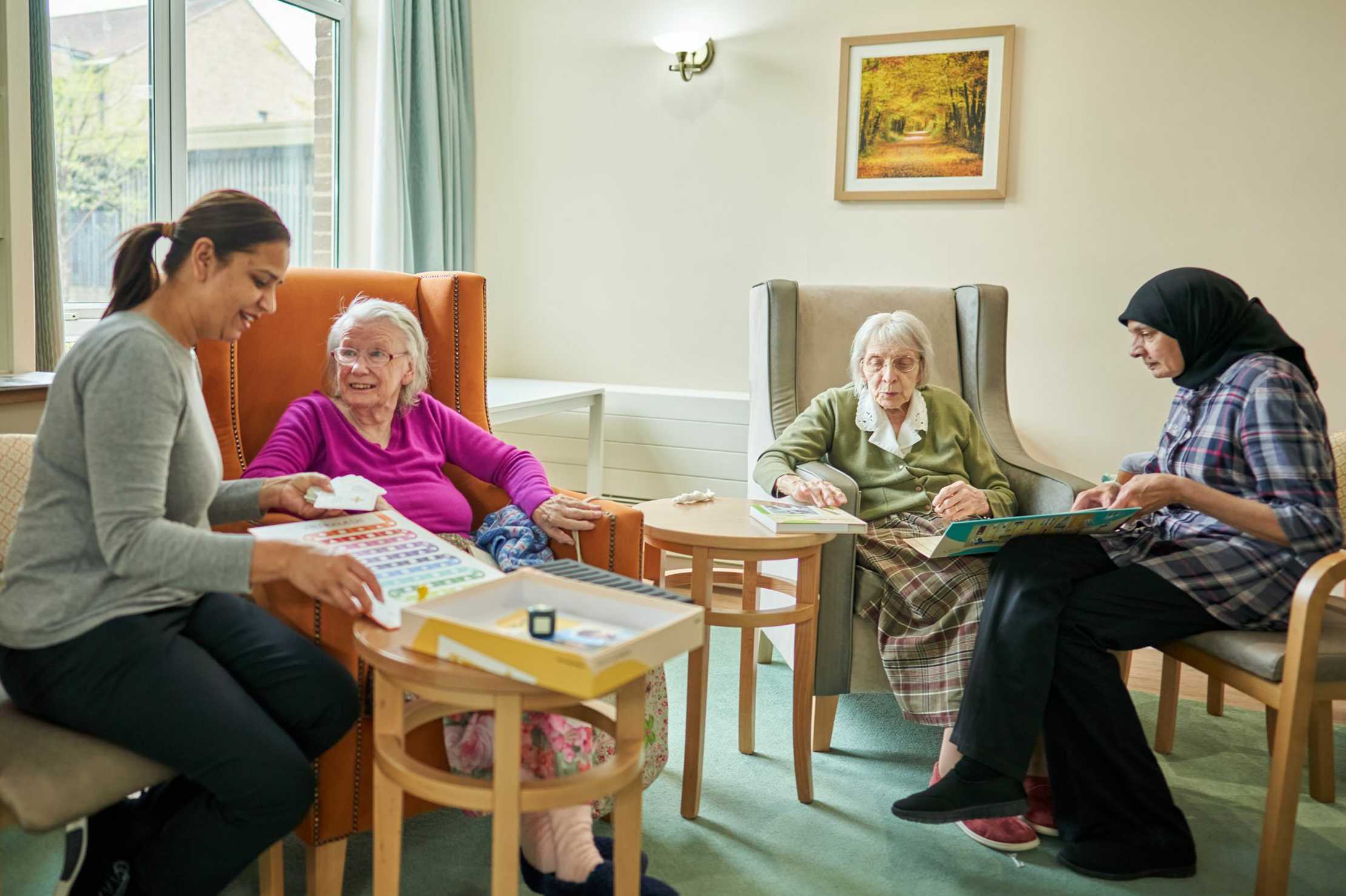 Two residents and two carers in Evington Home lounge