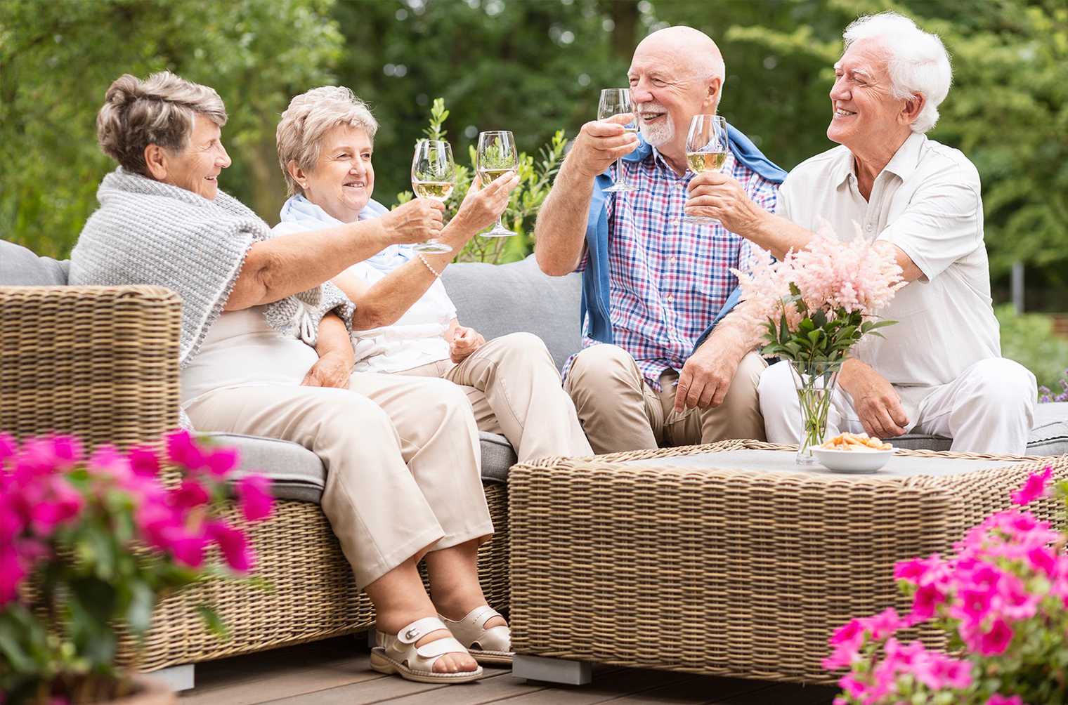 Four retirees enjoy drinks in the garden of their rental accommodation