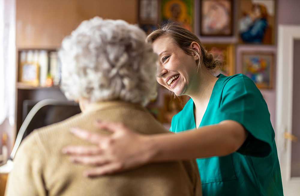 Elderly lady receiving private nursing care at home with nurse in green top