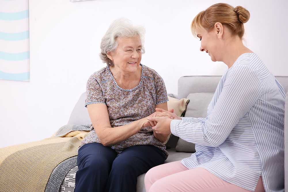 Middle aged lady offering care at home for elderly people to older woman