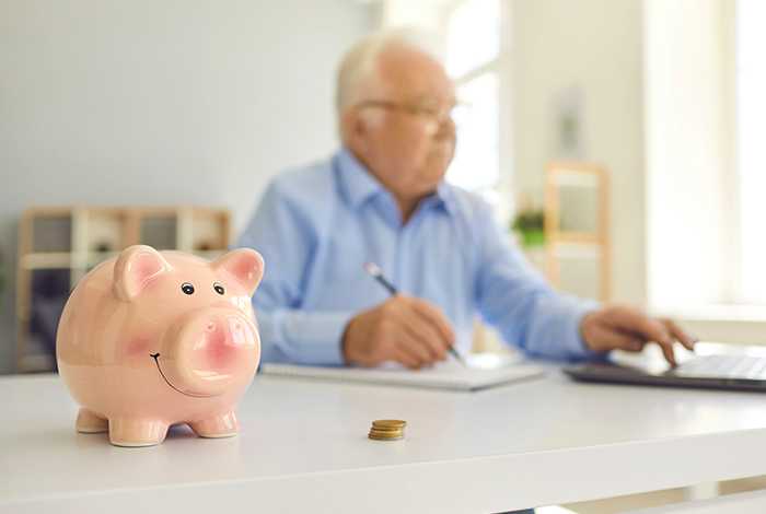 Piggy bank next to man working out pension